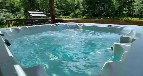 a jacuzzi tub in a backyard with blue water at Peaceful Pocono Home with Hot Tub, gym, & office in Long Pond