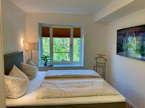 ein Schlafzimmer mit einem großen Bett mit Fenster in der Unterkunft Dünenwelle - 3 Zi, Kü, 2 Bäder, Balkon in Binz