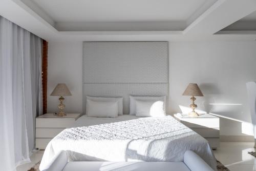 a white bedroom with a white bed and two lamps at Costa do Sol Boutique Hotel in Búzios
