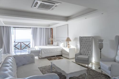 a white room with a bed and a couch and chairs at Costa do Sol Boutique Hotel in Búzios