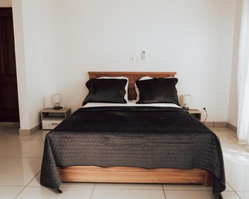 a bedroom with a bed with a black comforter at La RESIDENCE LES HIBISCUS in Djoungolo