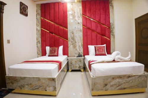 two beds in a room with red walls at Metro One Hotel in Lahore