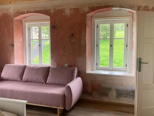 a purple couch in a room with two windows at Konírna Kovářská in Kovářská