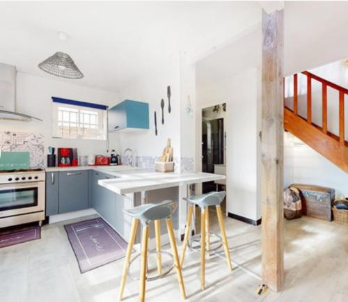 une cuisine avec des placards bleus et des tabourets dans l'établissement Maison typique royannaise dans un quartier calme, à Royan