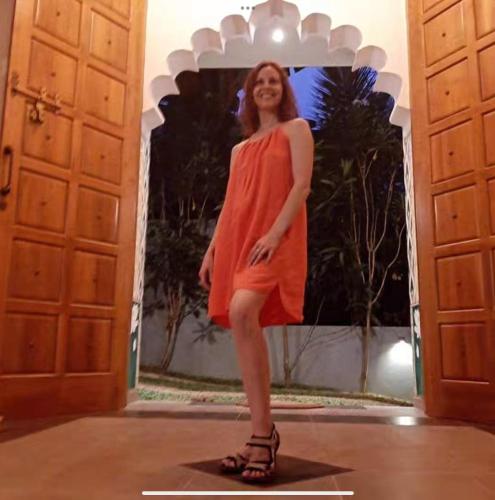 a woman in an orange dress standing between two doors at Barefoot Bungalow Hikka in Hikkaduwa