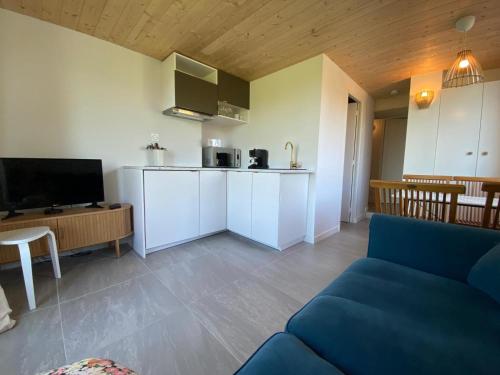 un salon avec un canapé bleu et une cuisine dans l'établissement Gites de la Baie d'Honfleur, à Cricquebœuf