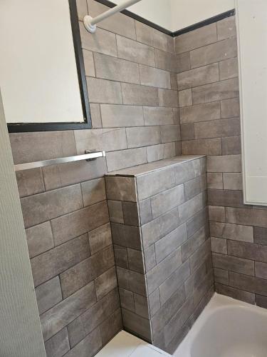 a bathroom with a gray tiled shower with a tub at TKC Homes in Irvington