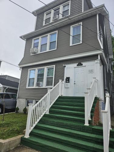 a gray house with a white door and stairs at TKC Homes in Irvington