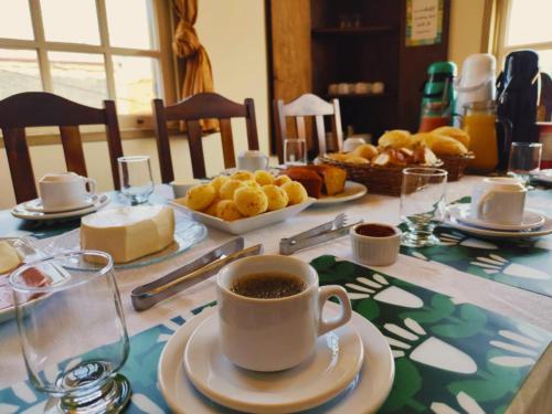 un tavolo con una tazza di caffè e un piatto di pane di Pousada Geraes - Sua casa longe de casa a Ouro Preto