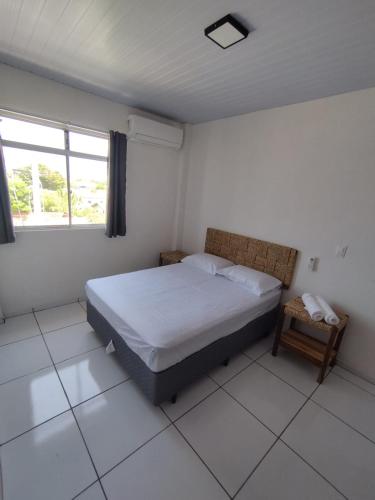 a white bedroom with a bed and a window at Loft aconchegante ao lado do Rio Poty Shopping in Teresina