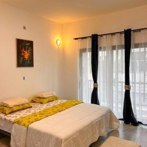 a bedroom with a bed and a window with curtains at Résidences LELYSSE in Méyo