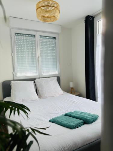 Agréable Studio proche Aéroport de Bordeaux في BOD: سرير ابيض عليه وسادتين خضراء