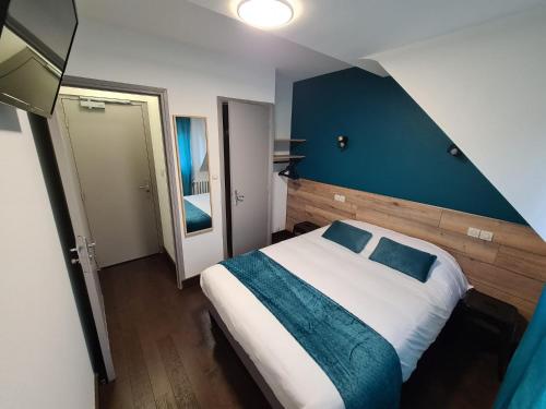 a bedroom with a large bed and a blue wall at Berry Hôtel La Châtre in La Châtre