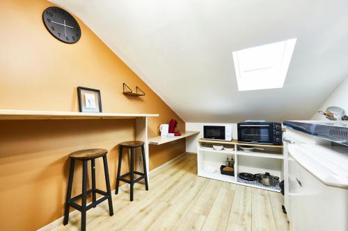 une cuisine avec deux tabourets de bar et une horloge sur le mur dans l'établissement RS-4 Studio dans les combles 1 pers - 4ème étage, à Mulhouse