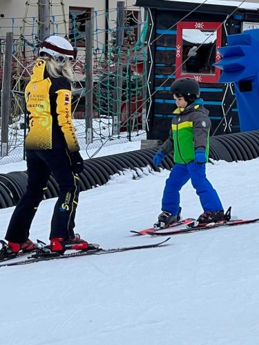a woman and a child on skis in the snow at WELLNESS Chalet OXY in Ždiar