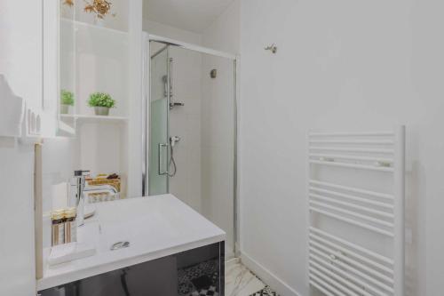 une salle de bain blanche avec un lavabo et une douche dans l'établissement Charming apartment - 1BD-4P - Gare du Nord, à Paris