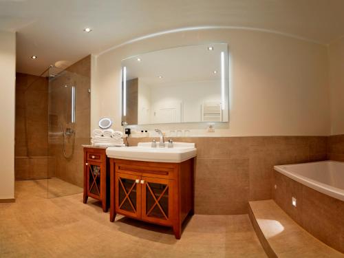 ein Badezimmer mit einem Waschbecken, einer Badewanne und einem Spiegel in der Unterkunft Hotel Restaurant Kohlbrecher Villeroy & Boch SPA in Osnabrück