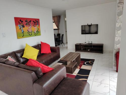 a living room with two leather couches and a tv at 304 Amazibu- Luxury On the Beach in Amanzimtoti