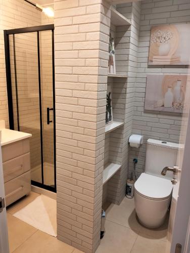 a bathroom with a toilet and a white brick wall at Warm Harbor in Santa Coloma de Gramanet