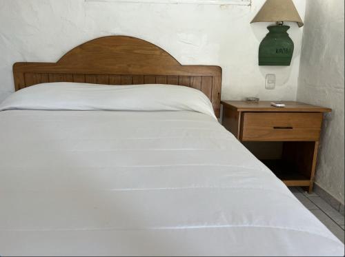 a bedroom with a white bed and a nightstand with a green lamp at El Kaoba in Cabarete