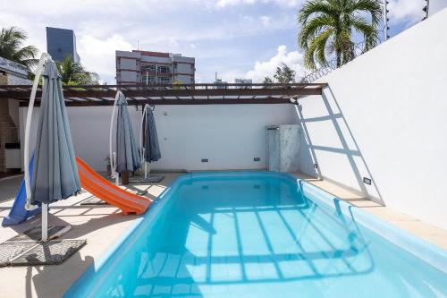 a swimming pool with a ladder and umbrellas on a building at Casa Jardim - Praia do Bessa por Carpediem in João Pessoa