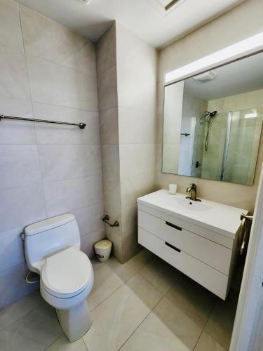 a bathroom with a toilet and a sink and a mirror at 7Mile Beachfront Apartment in George Town