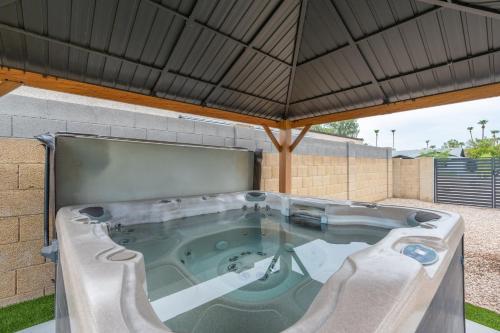 a hot tub in a backyard with an umbrella at 6 Bed Luxury Heated Pool in Phoenix