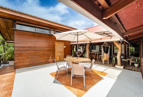 a patio with a table and chairs and an umbrella at La Flor de Coco in Sámara