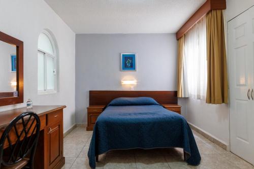 a bedroom with a bed and a desk and a window at Hotel Qualitel Plus in Morelia