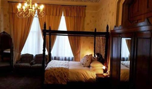 a bedroom with a canopy bed and two windows at The Royal Hotel Tain in Tain