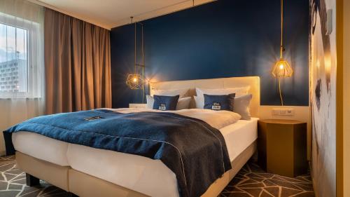a bedroom with a large bed with a blue wall at Holiday Inn - the niu, Ridge Halle Central Station by IHG in Halle an der Saale