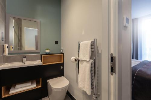 a bathroom with a sink and a toilet and a mirror at Holiday Inn - the niu, Loom Manchester North by IHG in Manchester