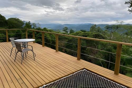 a wooden deck with a table and chair on a balcony at Chalé dos Alpes 2 hidromassagem e Lareira in Santo Amaro da Imperatriz