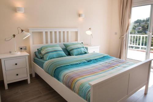 Un dormitorio blanco con una cama y una ventana. en SeaHomes Vacations - Seafront Apt Fenals with PKG, en Lloret de Mar