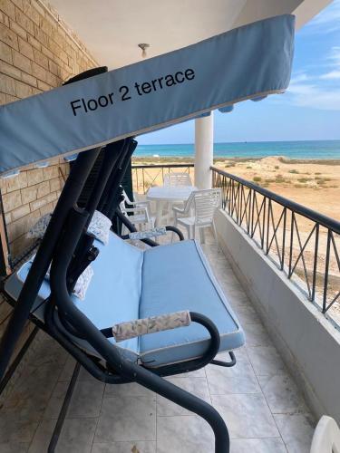 a chair on a balcony with the ocean in the background at First Row Sea-Front Chalets Media Village in Marsa Matruh