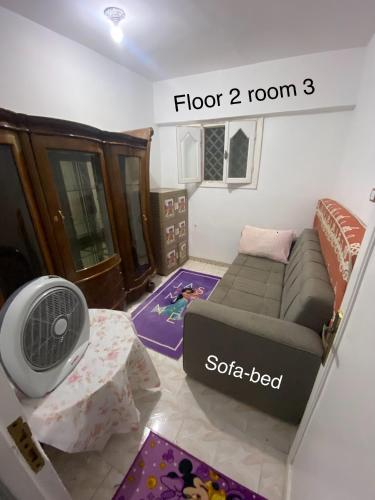 a living room with a couch and a fan at First Row Sea-Front Chalets Media Village in Marsa Matruh