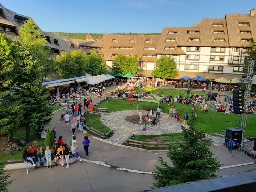 a group of people walking around a park in front of a building at Star Apartments Konaci in Kopaonik