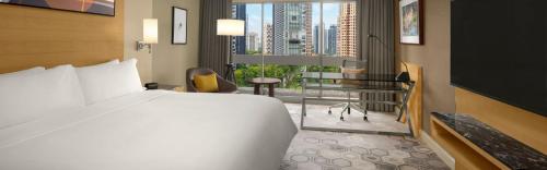 a hotel room with a large bed and a desk at voco Orchard Singapore by IHG in Singapore