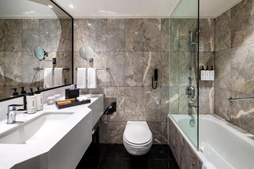 a bathroom with a sink and a tub and a toilet at voco Orchard Singapore by IHG in Singapore