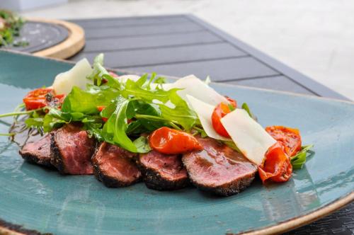 a plate of food with meat and vegetables on a table at voco Orchard Singapore by IHG in Singapore
