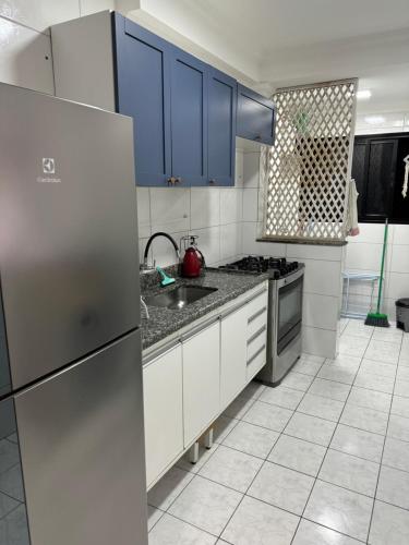 a kitchen with blue cabinets and a stainless steel refrigerator at Edifício Gorja in Praia Grande