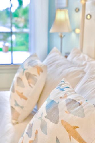 a bed with white sheets and pillows with a window at Villa la Rive, River Villa in Le Temple-sur-Lot