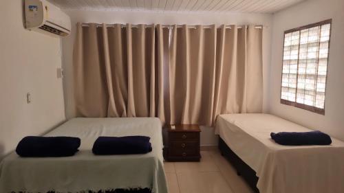 Habitación con 2 camas y ventana con cortinas. en Casa de praia em Piratininga, en Niterói