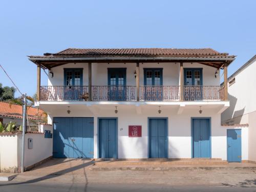 a white building with blue doors and a balcony at Casa da Tuta Pousada in Tiradentes