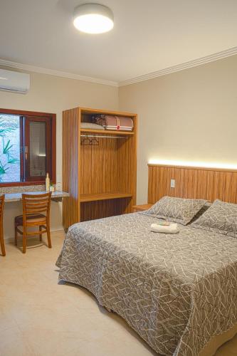 a bedroom with a bed and a table and a chair at Pousada Essência do Vale in Cruzeiro