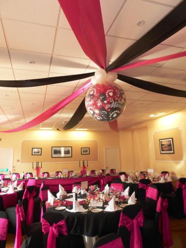 a banquet hall with tables with pink and black bows at The Royal Hotel Tain in Tain