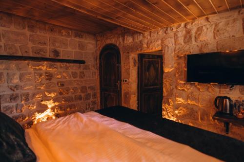 a bedroom with a bed and a tv on a brick wall at İsadora Cave Cappadocia in Nevsehir