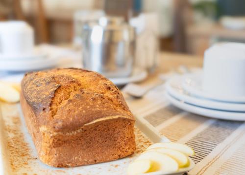 a loaf of bread on a cutting board with sliced apples at Casa da Tuta Pousada in Tiradentes