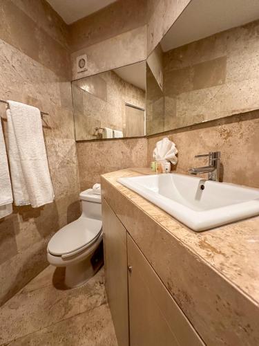 a bathroom with a white toilet and a sink at Hotelito del Mar Playa del Carmen in Playa del Carmen