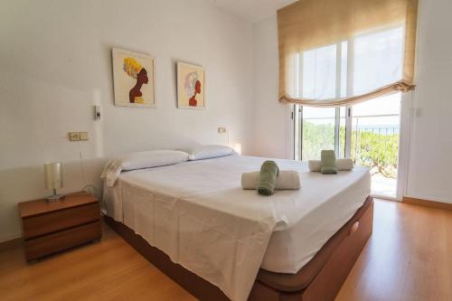 a bedroom with a large bed with white sheets and a window at SeaHomes Vacations - Seafront Apt in Blanes with PKG in Blanes